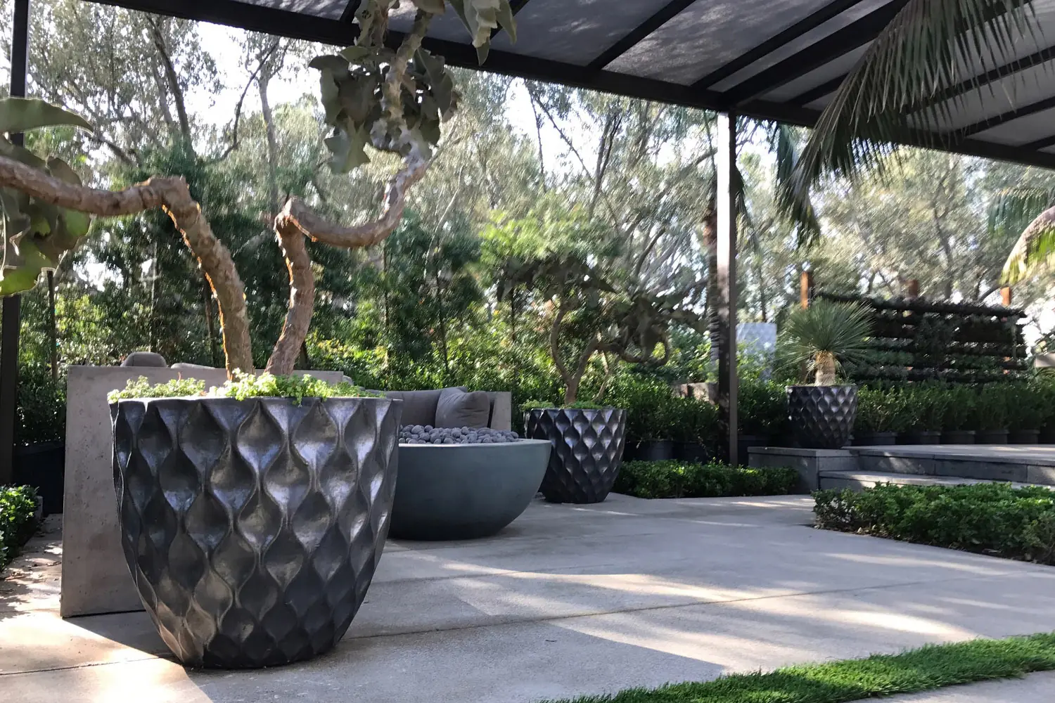 Outdoor living room with sculptural black planters and courtyard landscape