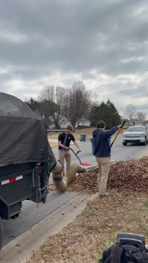 Keller Lawns crew raking and loading a large pile of fall leaves at a Harrisburg, NC home
