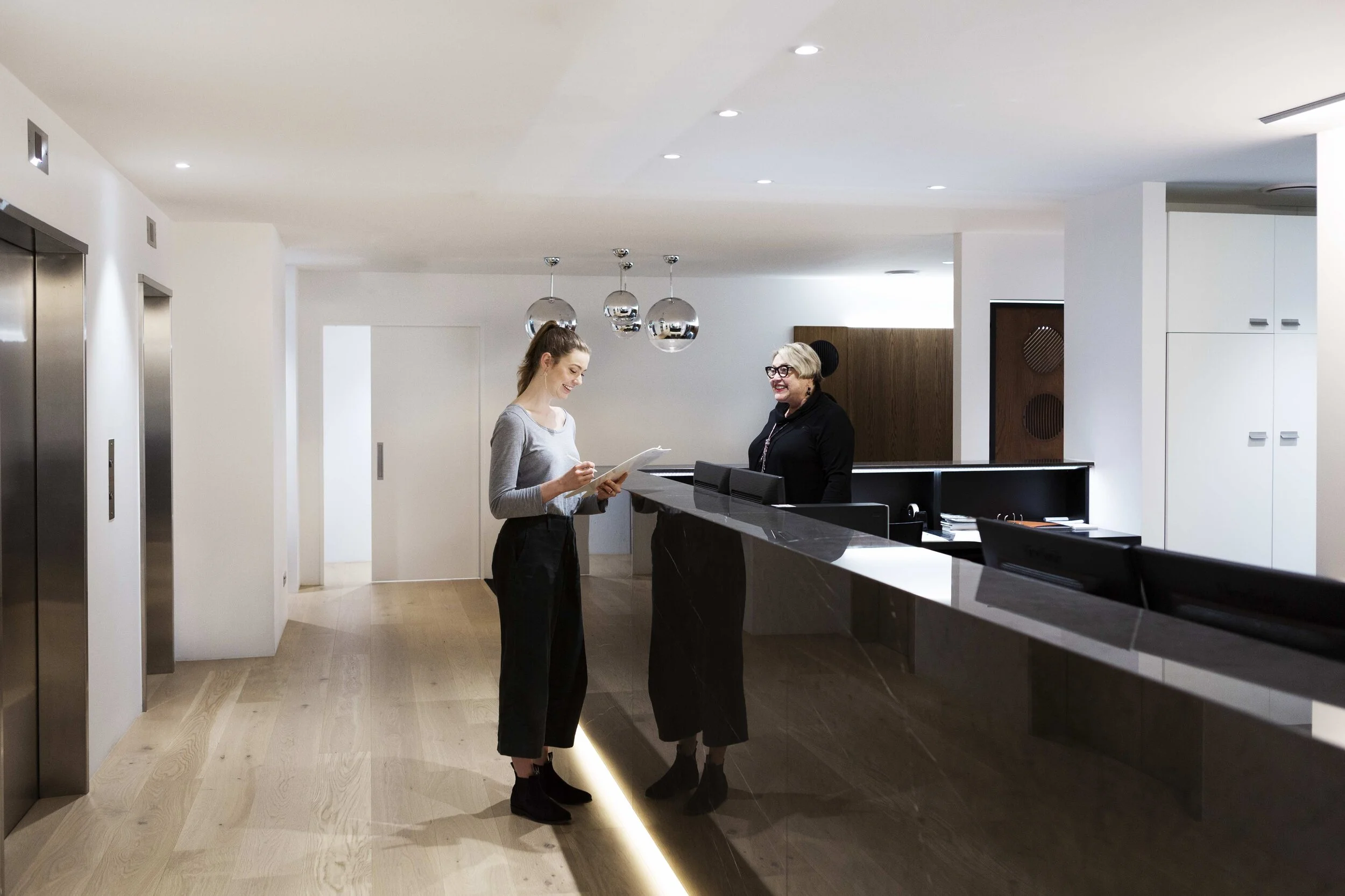 Patient speaking with a receptionist at a modern dental clinic front desk.