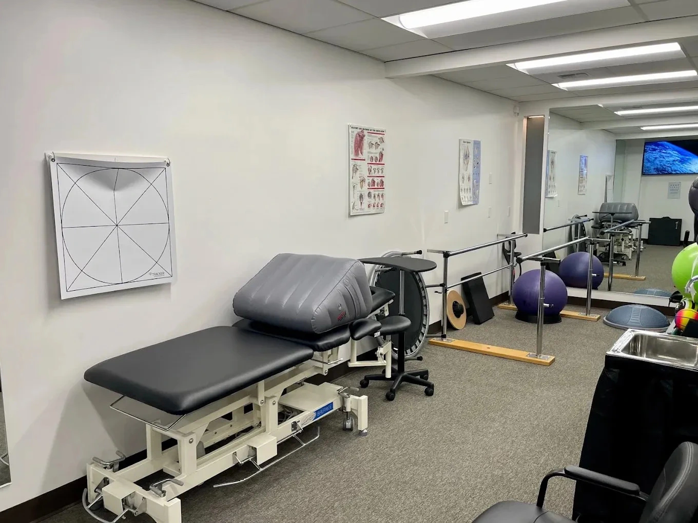 Spacious therapy gym area with modern equipment and parallel bars