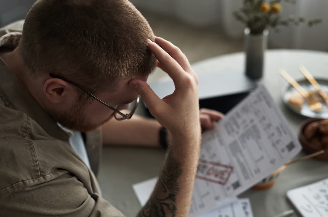 An employee at their kitchen table, worried over a past-due bill