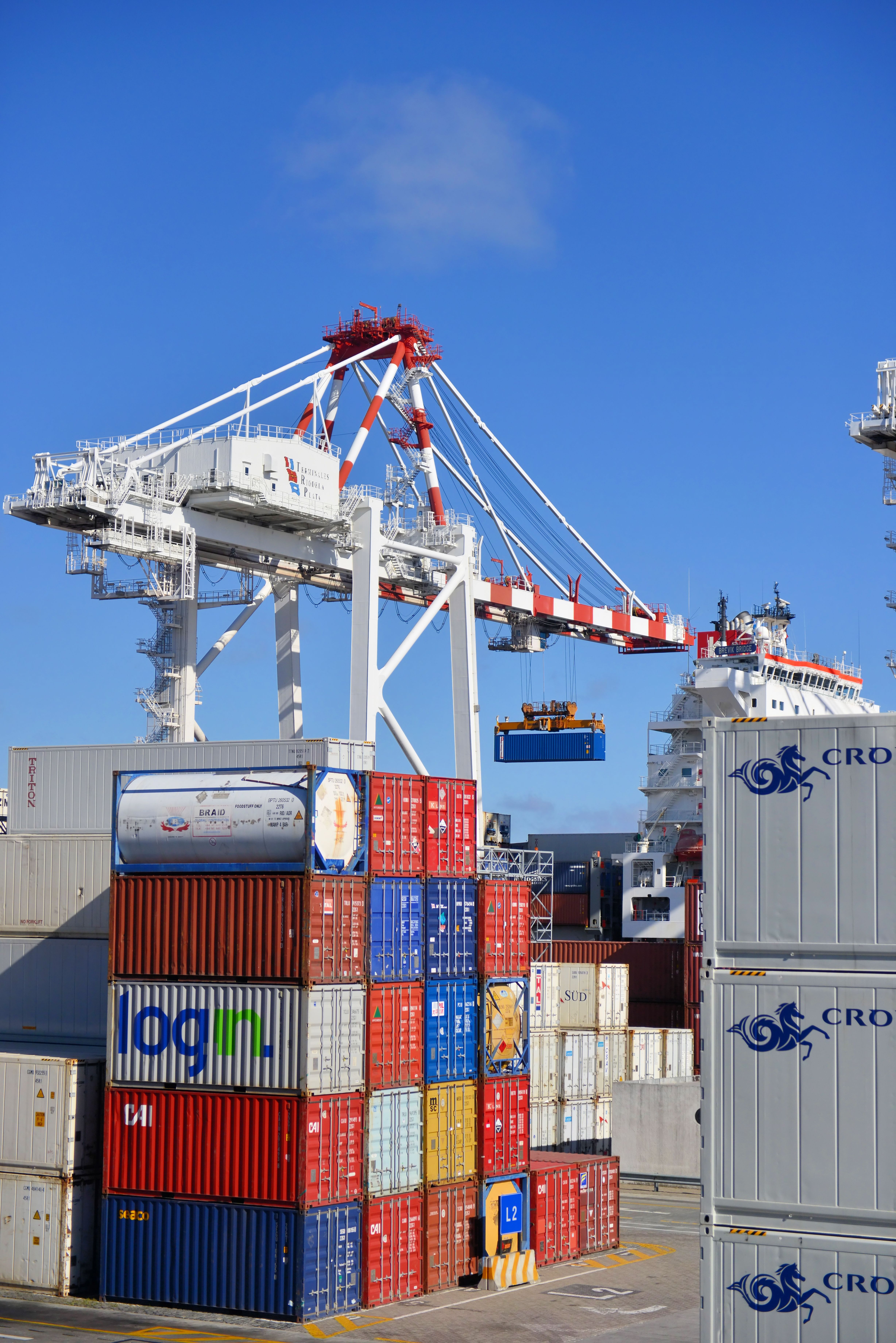 Quayside crane lifting a shipping container above stacked containers