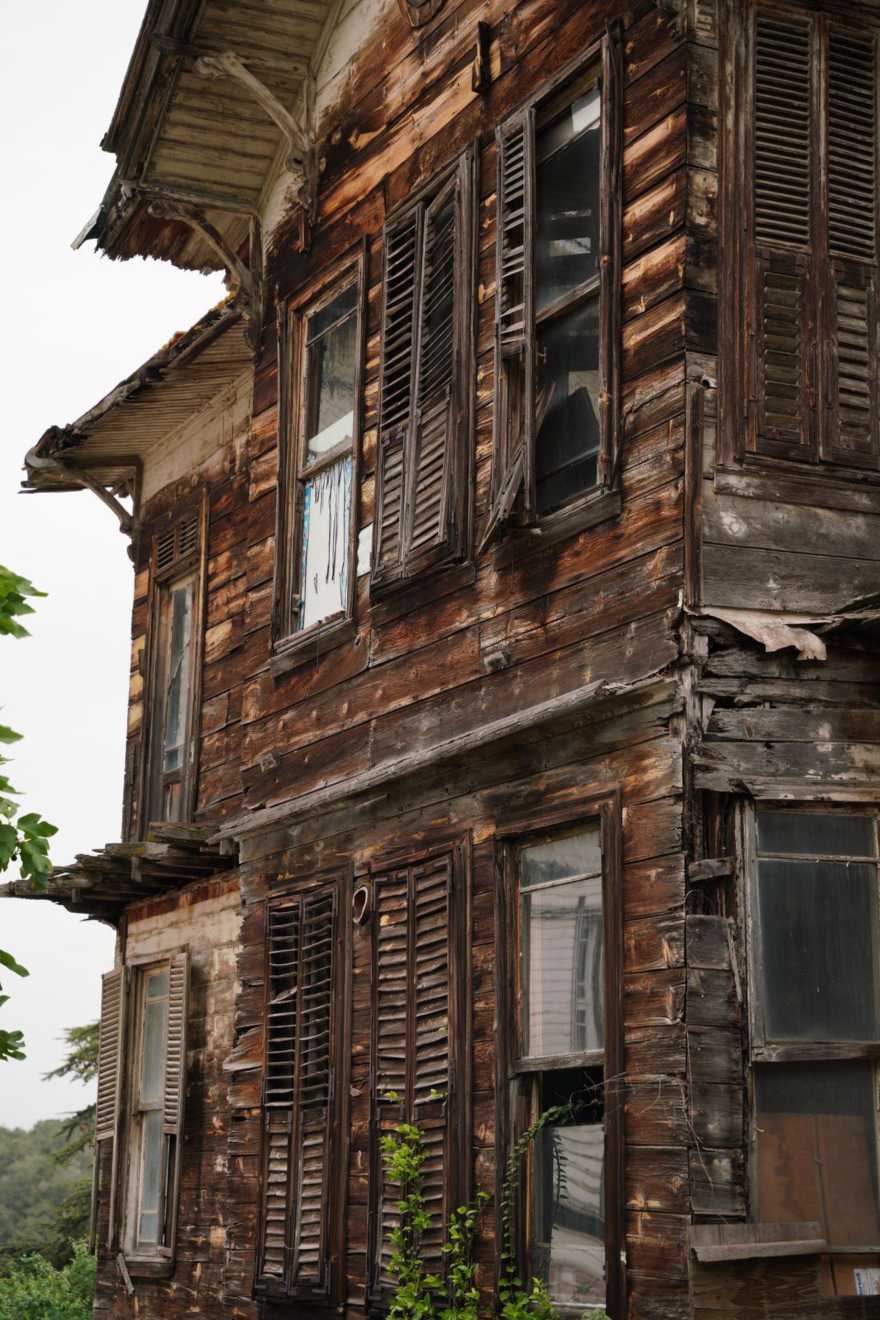 Neglected older wooden home with broken shutters
