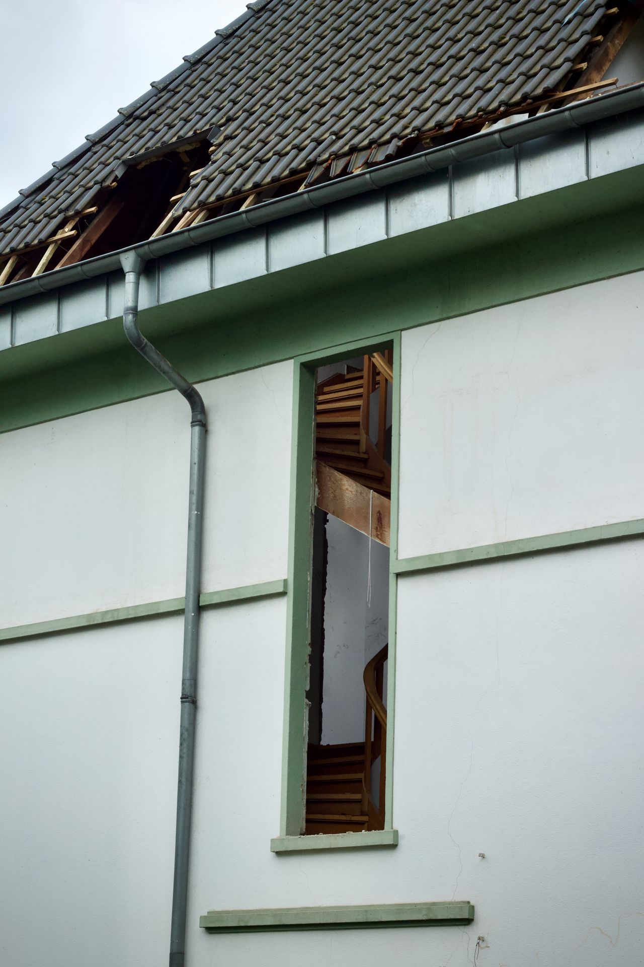 House with storm-damaged roof and open window