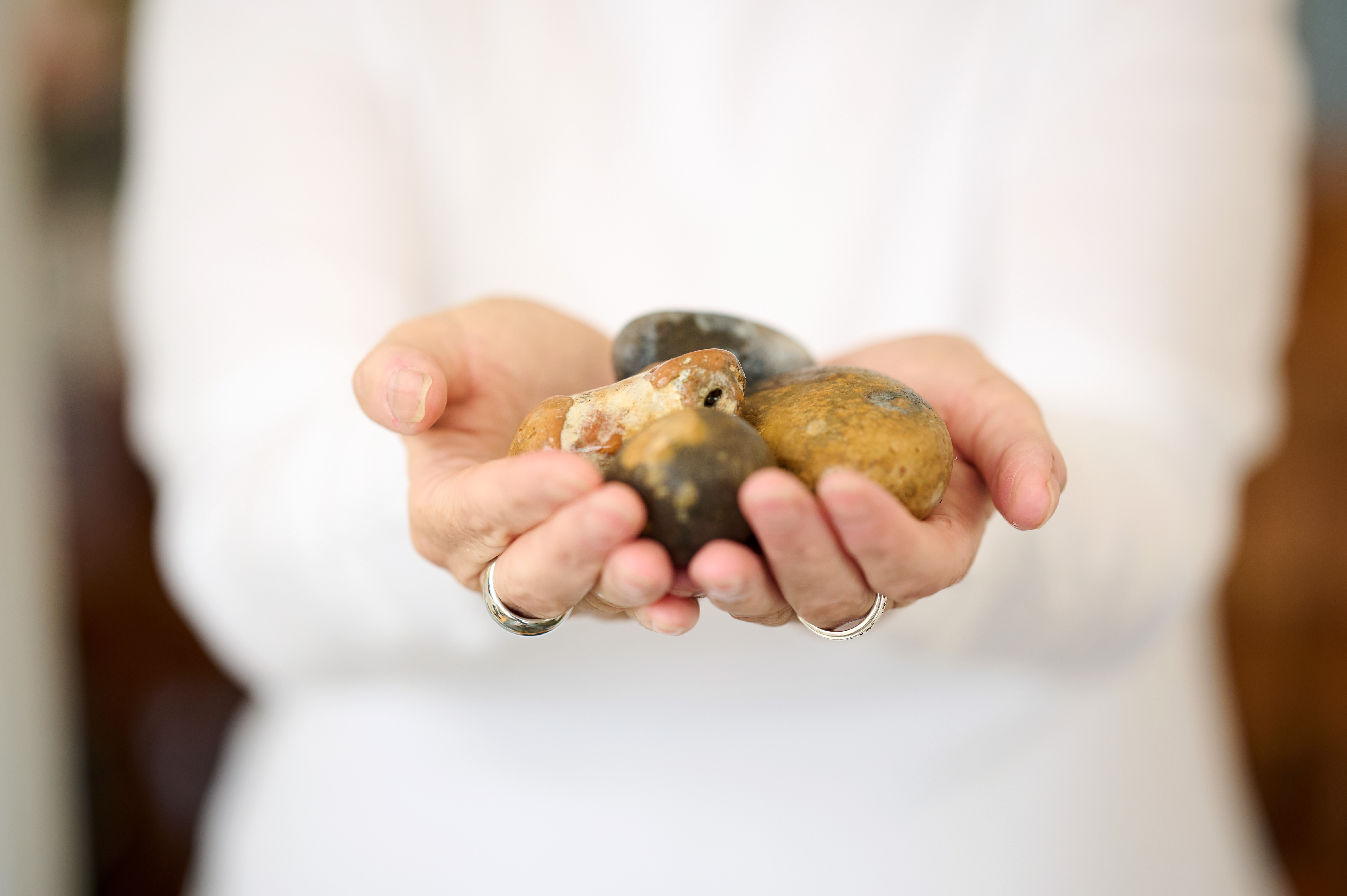 Hands holding several smooth stones