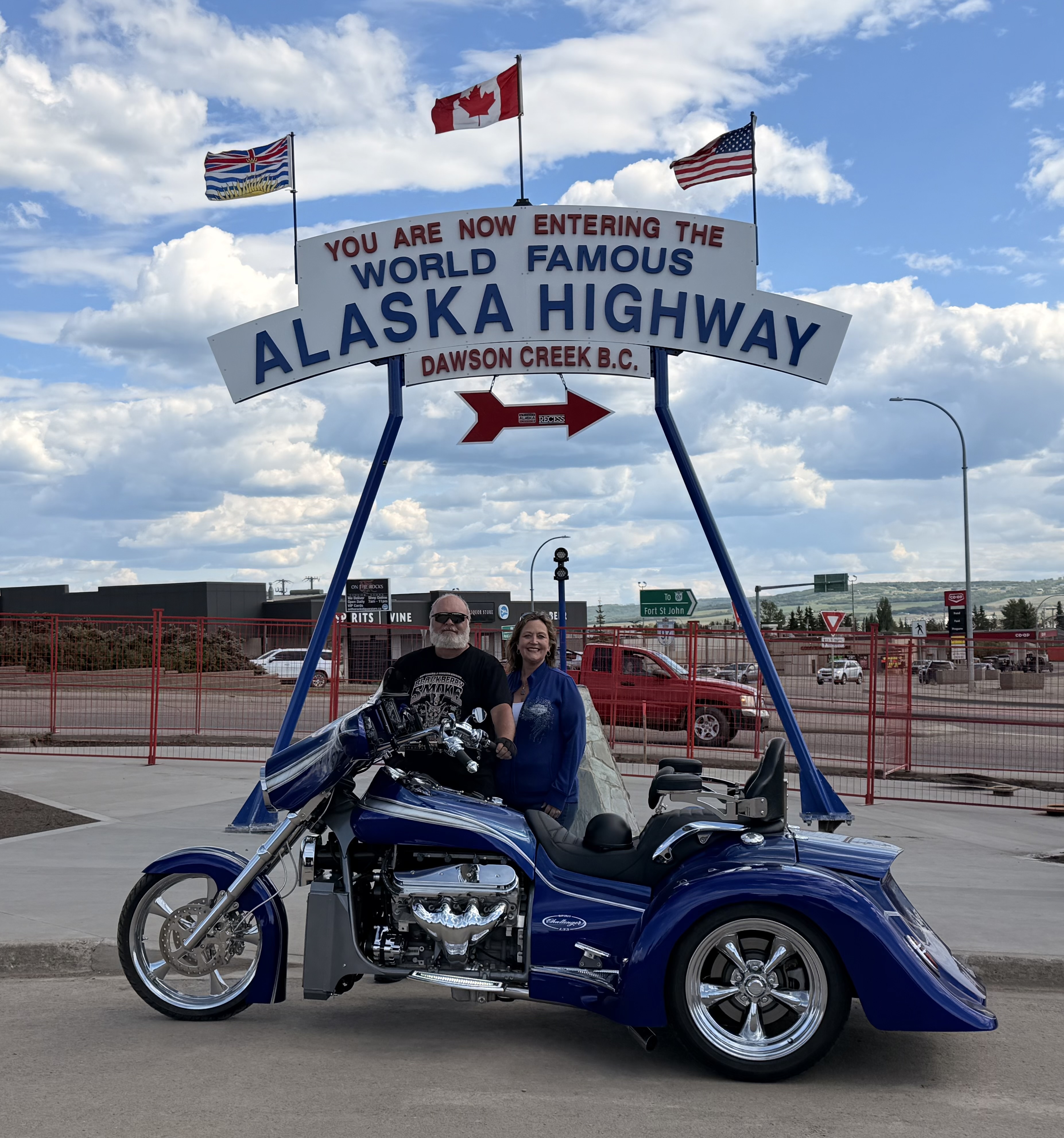 Owners on a Challenger at the Alaska Highway sign