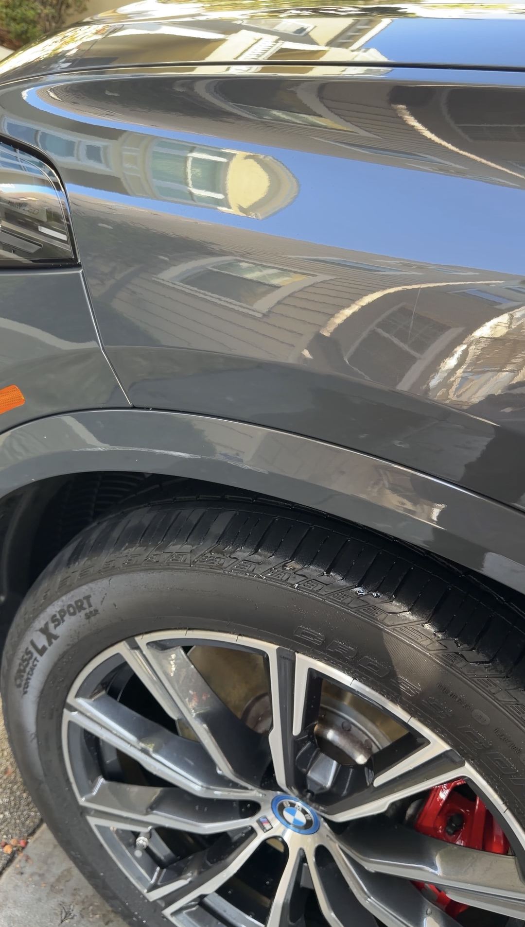 Front right wheel arch of a dark grey BMW X5 after scuff removal, the arch lip clean and glossy