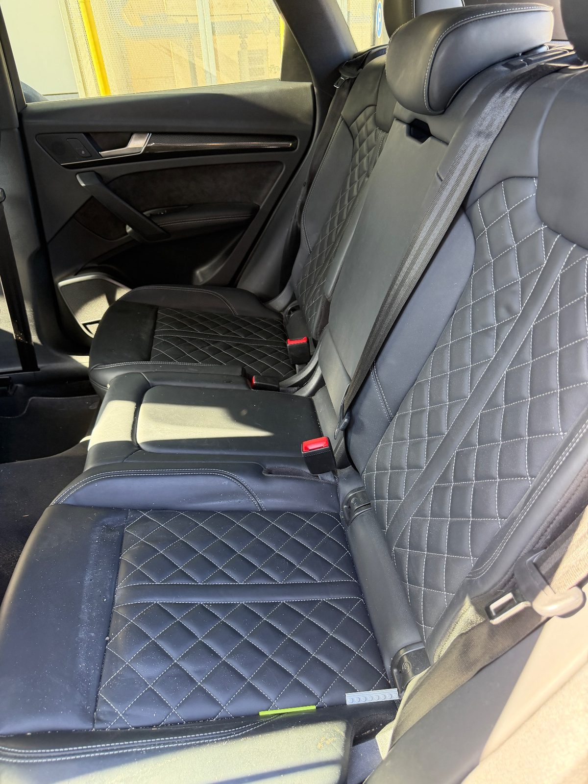 Rear leather seat of an Audi SQ5 before cleaning, with dust and crumbs on the cushion