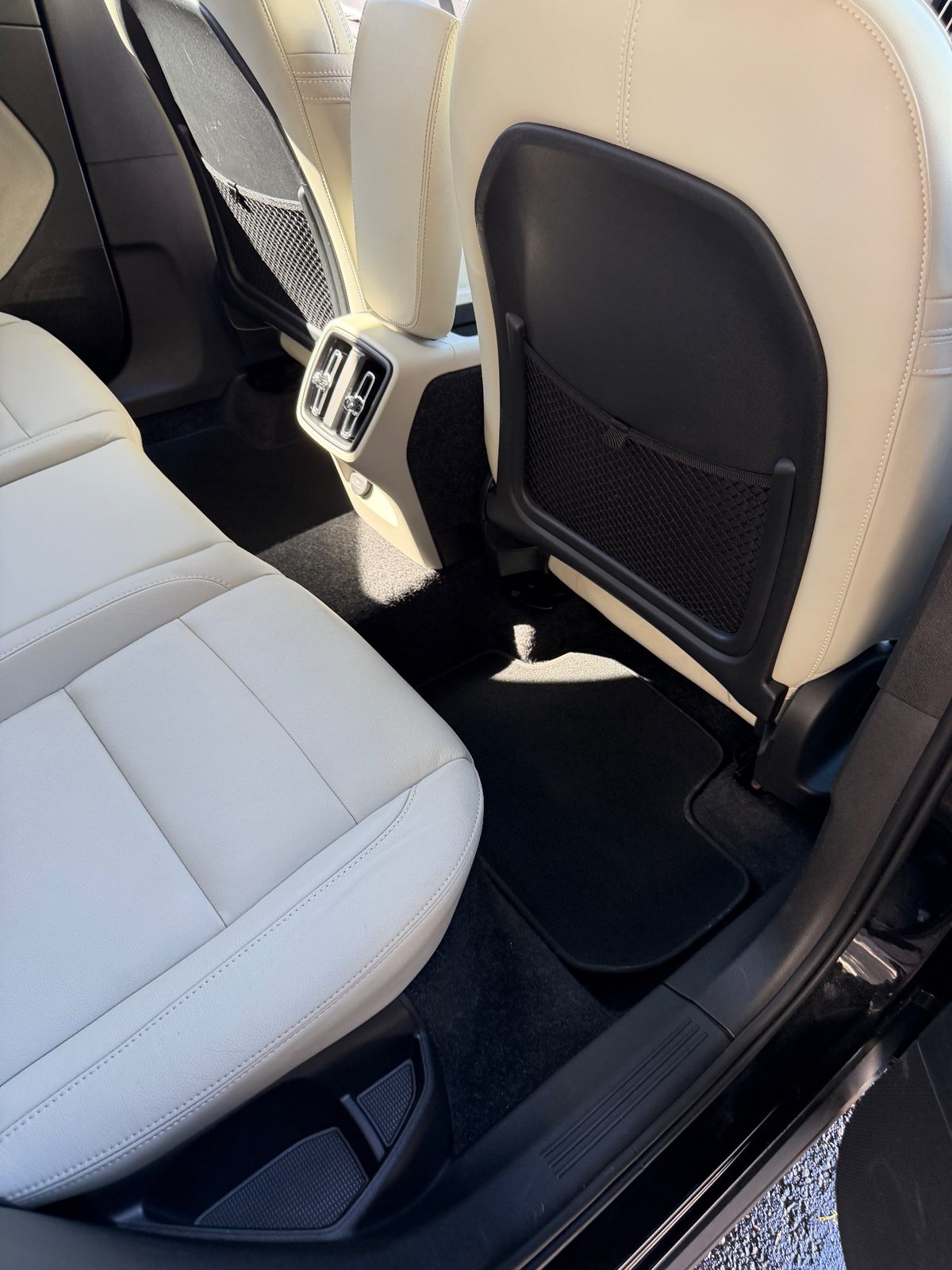 Clean rear footwell of a Volvo XC40 after detailing, with a hair-free black mat and carpet