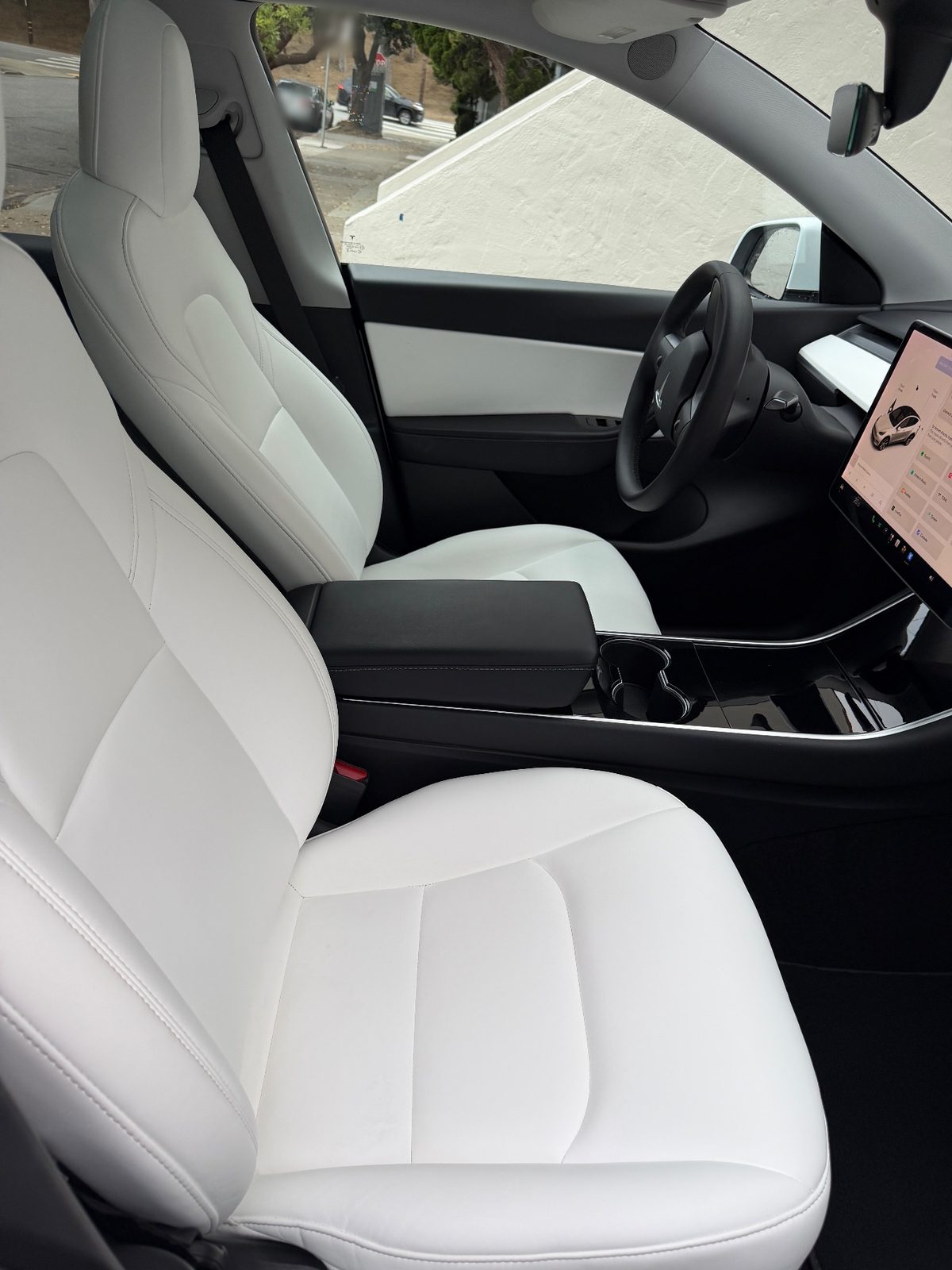Front passenger seat of a white Tesla Model Y after detailing, with clean white seats