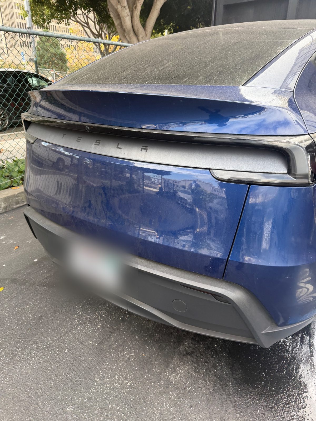 Dusty rear and bumper of a blue Tesla Model Y before detailing