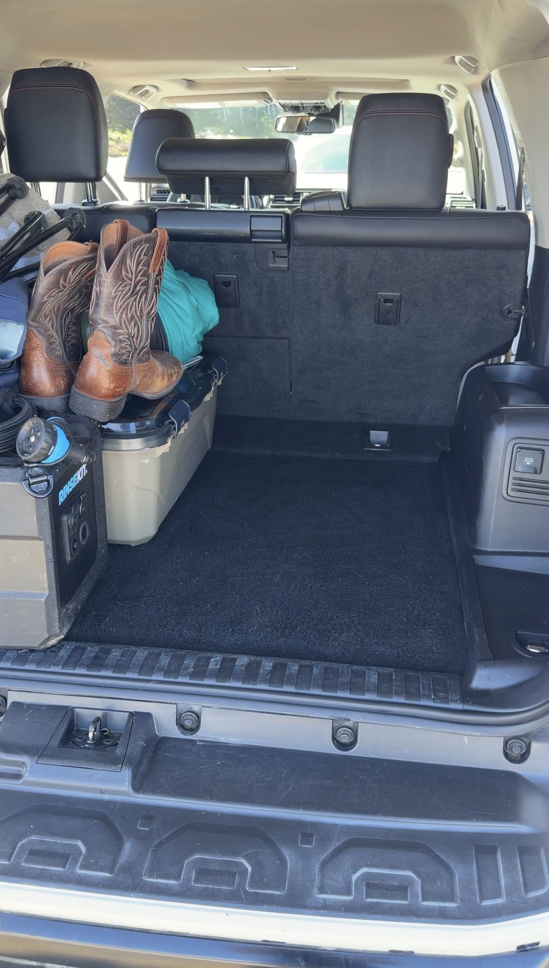 Clean cargo floor and rear bumper step of a Toyota 4Runner with boots and gear stacked on one side