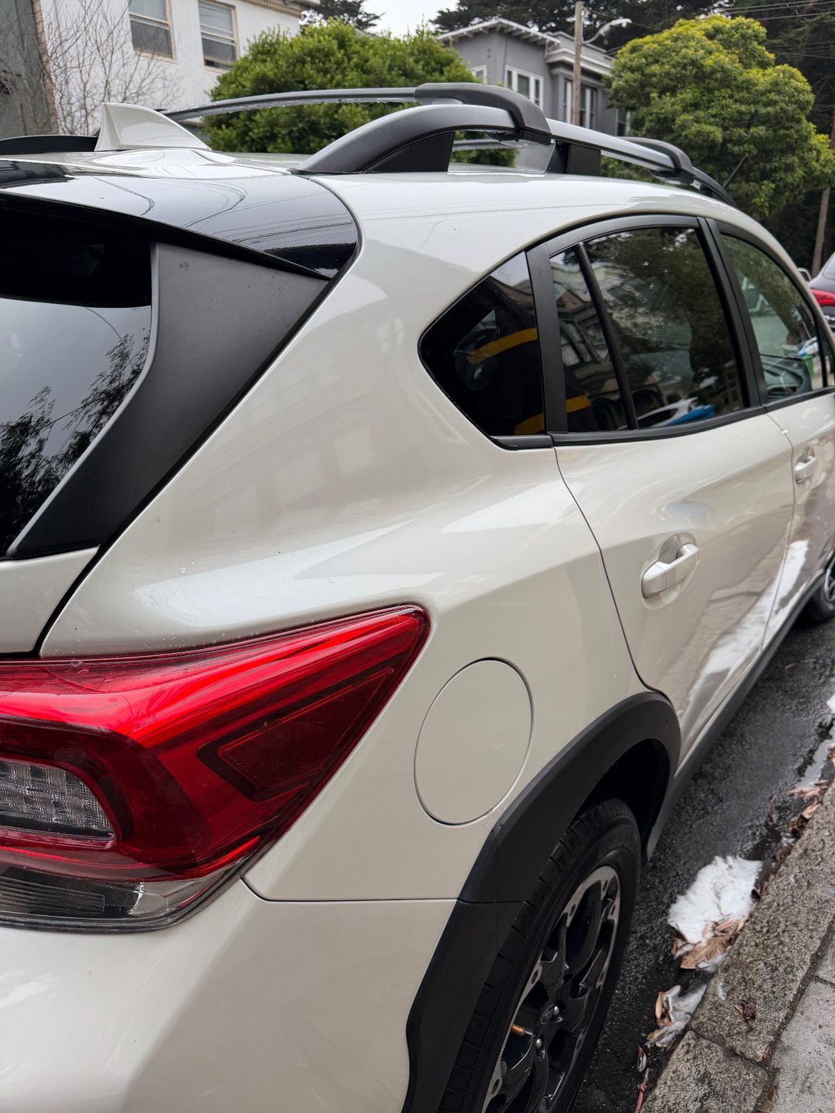 Clean glossy curb-side rear quarter of a white Subaru Crosstrek after washing