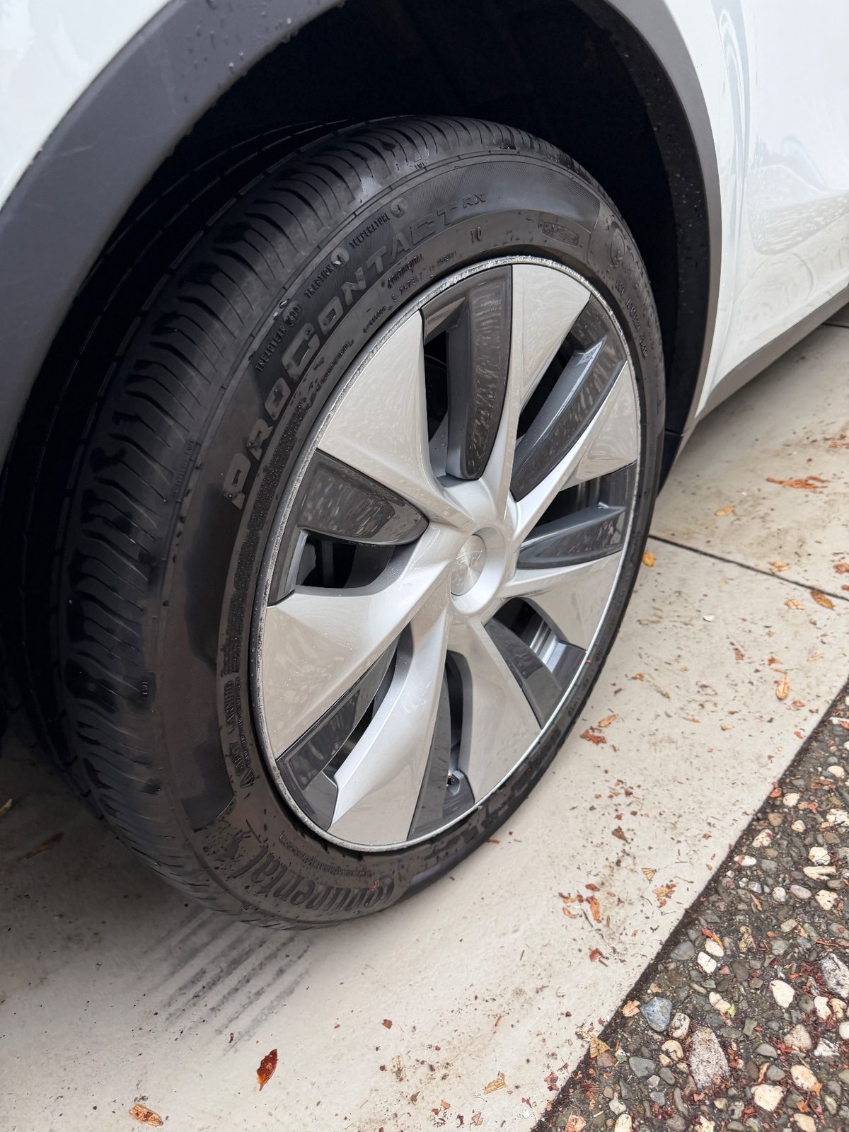 Front wheel of a white Tesla Model Y after detailing, with a black dressed tyre and a clean wheel cover