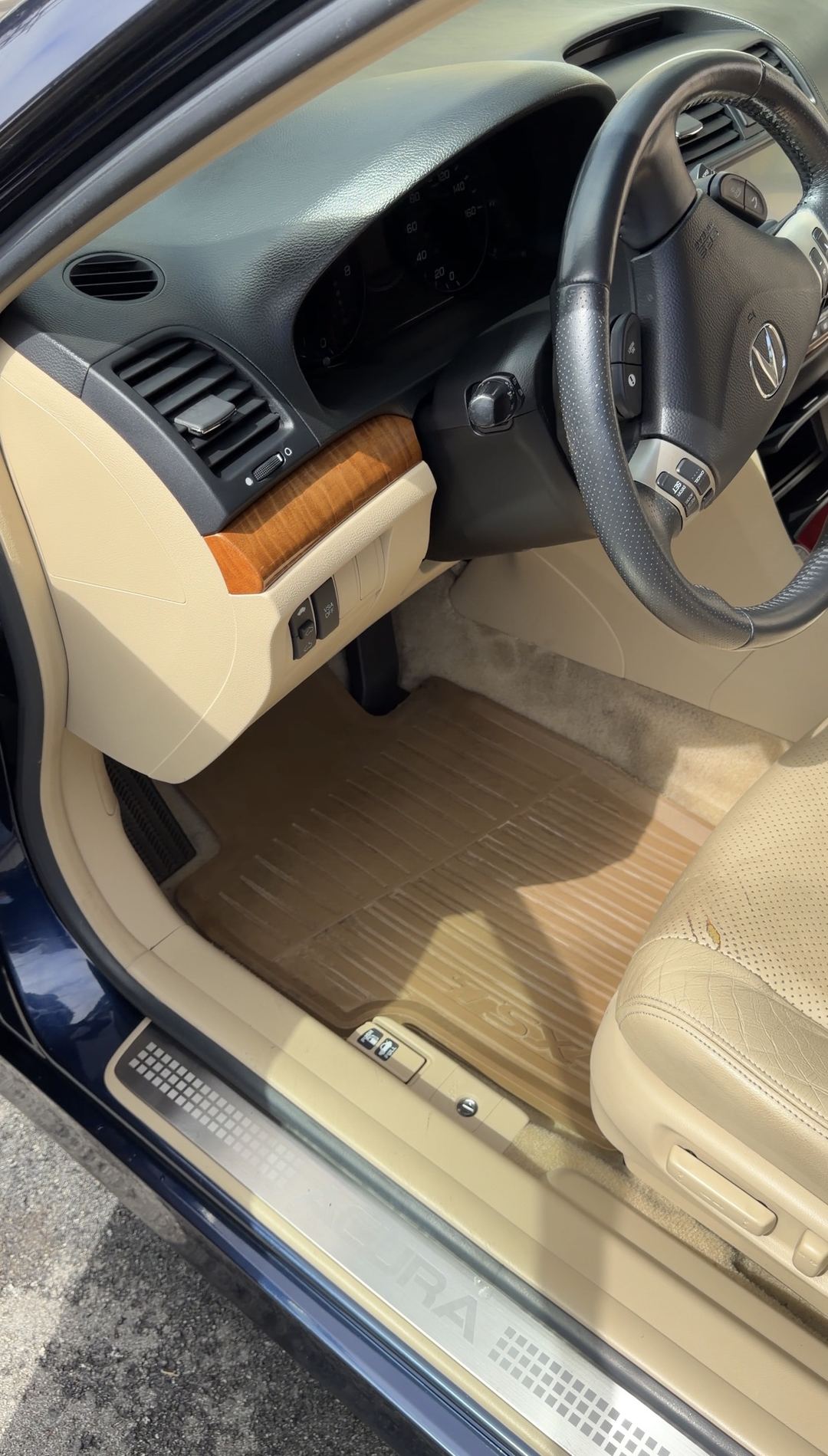 Cleaned driver's footwell of an Acura TSX after detailing, showing the TSX-branded rubber floor mat and a dust-free dashboard.