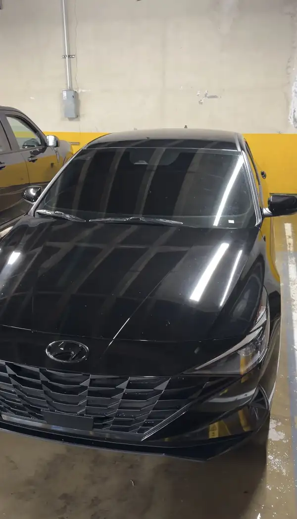 Front of a washed black Hyundai Elantra with a glossy hood in a parking garage