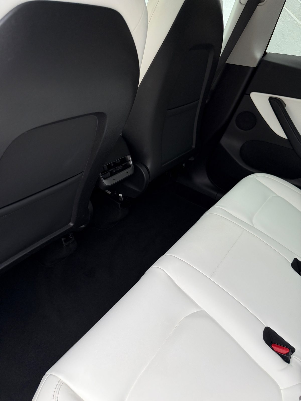 Clean rear footwell and seat backs of a white Tesla Model Y after detailing