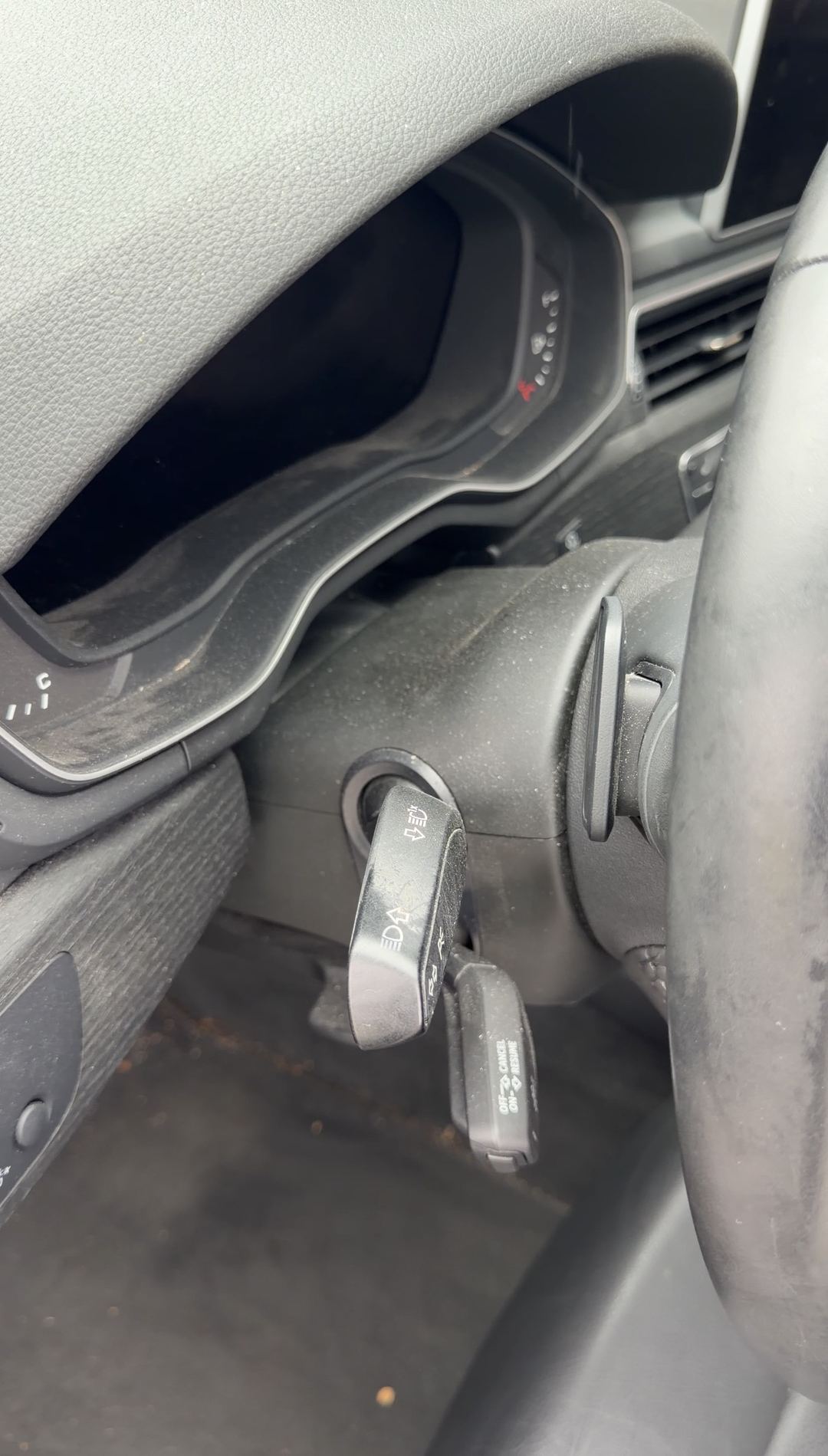 Dusty steering column and unlit instrument cluster of an Audi A4 seen past the wheel rim