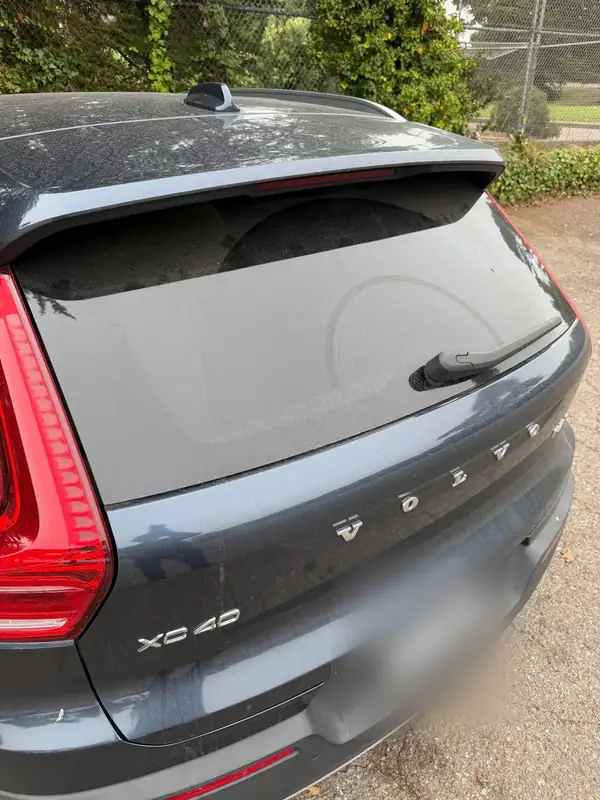 Rear of a Volvo XC40 before washing, with a thick dust film on the tailgate glass