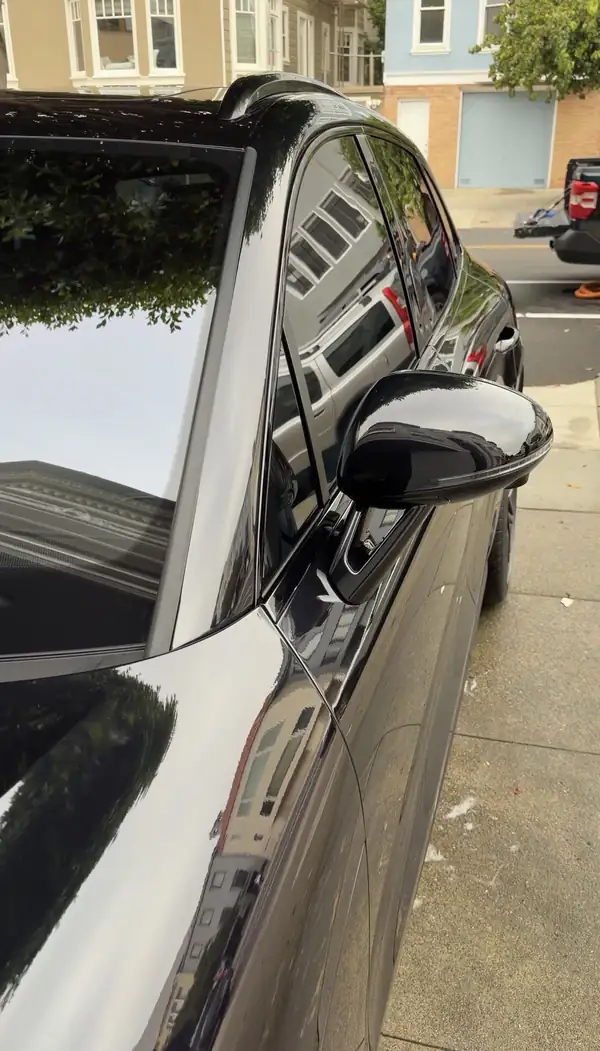 Spotless windshield and gloss-black mirror of a black Porsche Macan GTS after a San Francisco mobile detail.