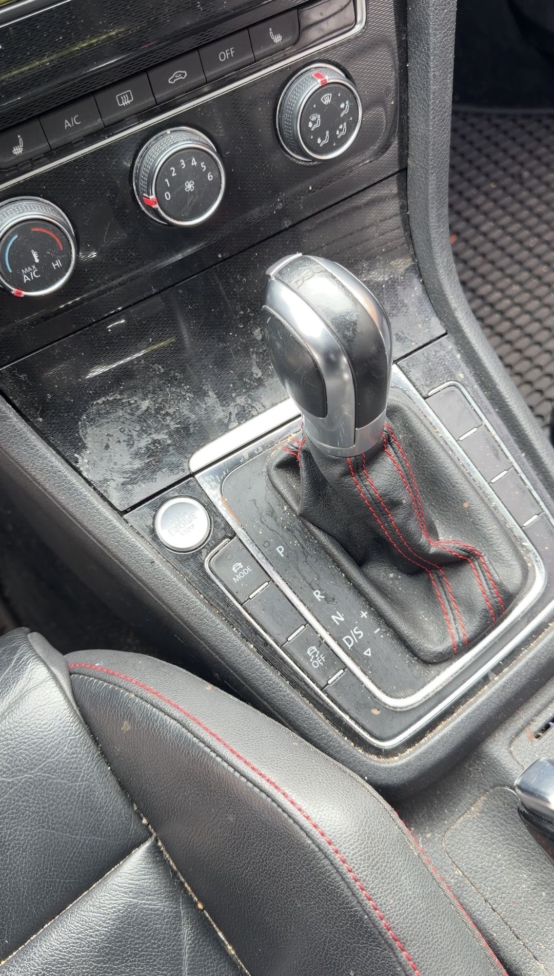 Shift lever area of a VW GTI before cleaning, grit and dust on the gloss trim