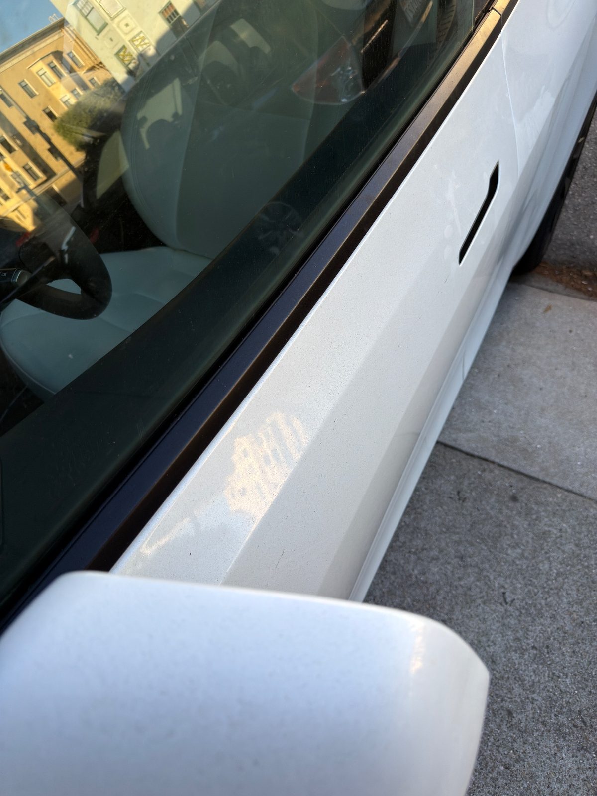 Spotted driver door of a white Tesla Model Y before cleaning