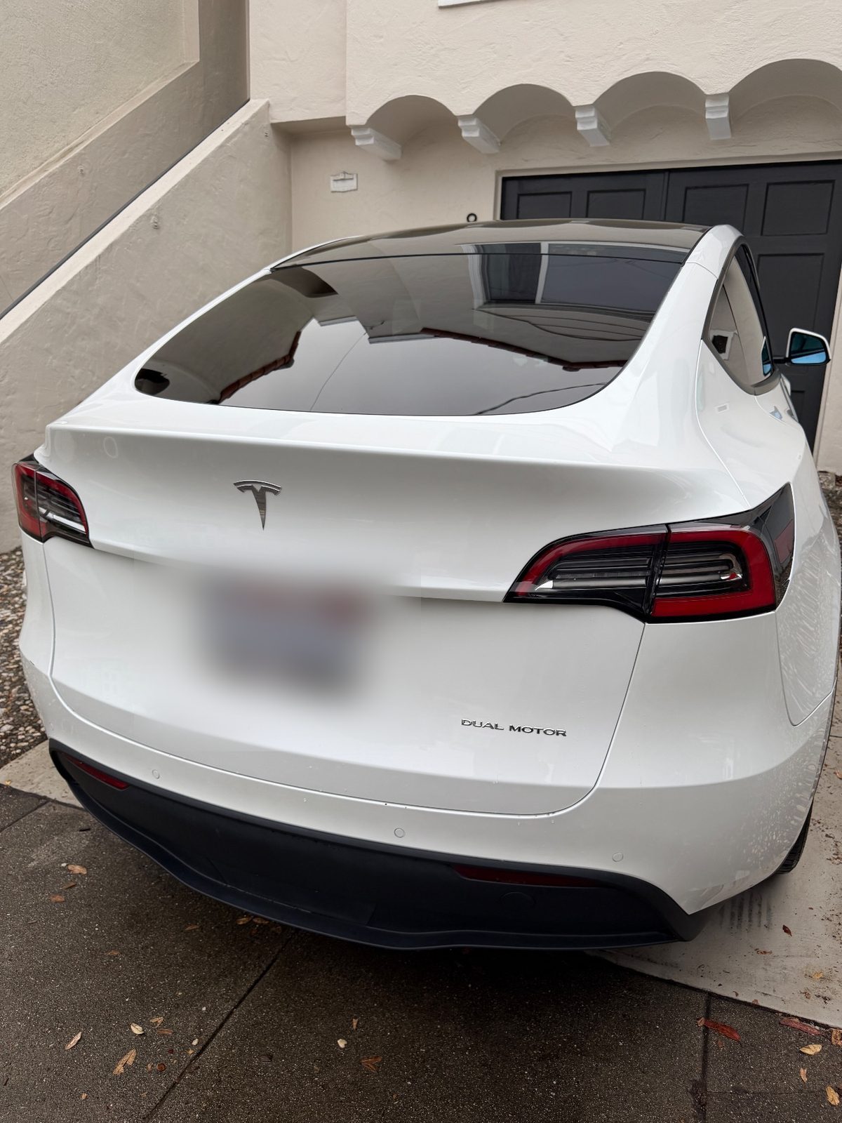 Rear of a white Tesla Model Y after detailing, with a clean rear window and tailgate