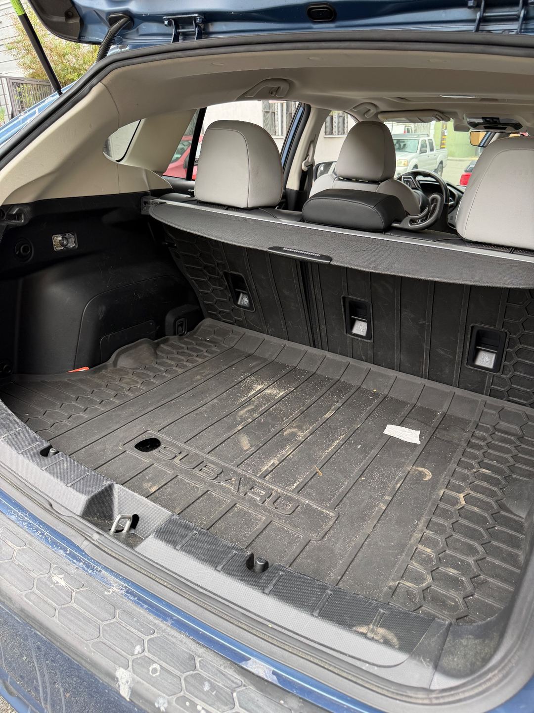 Cargo area of a Subaru Crosstrek before detailing, with dried dirt smeared across the rubber cargo tray