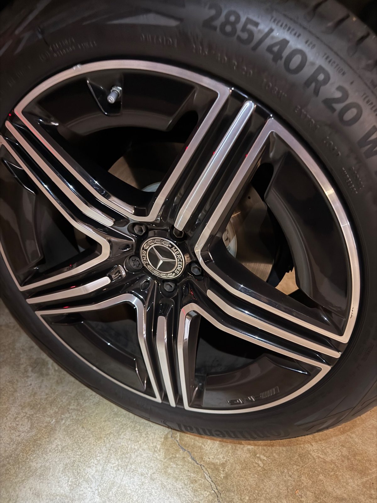 Black and machined alloy wheel on a white Mercedes GLC before cleaning, light dust on the rim