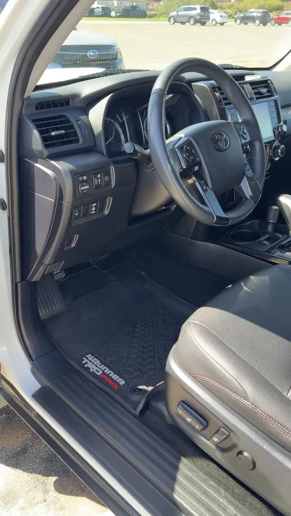Clean driver seat, floor mat and dashboard of a Toyota 4Runner TRD Pro seen through the open door