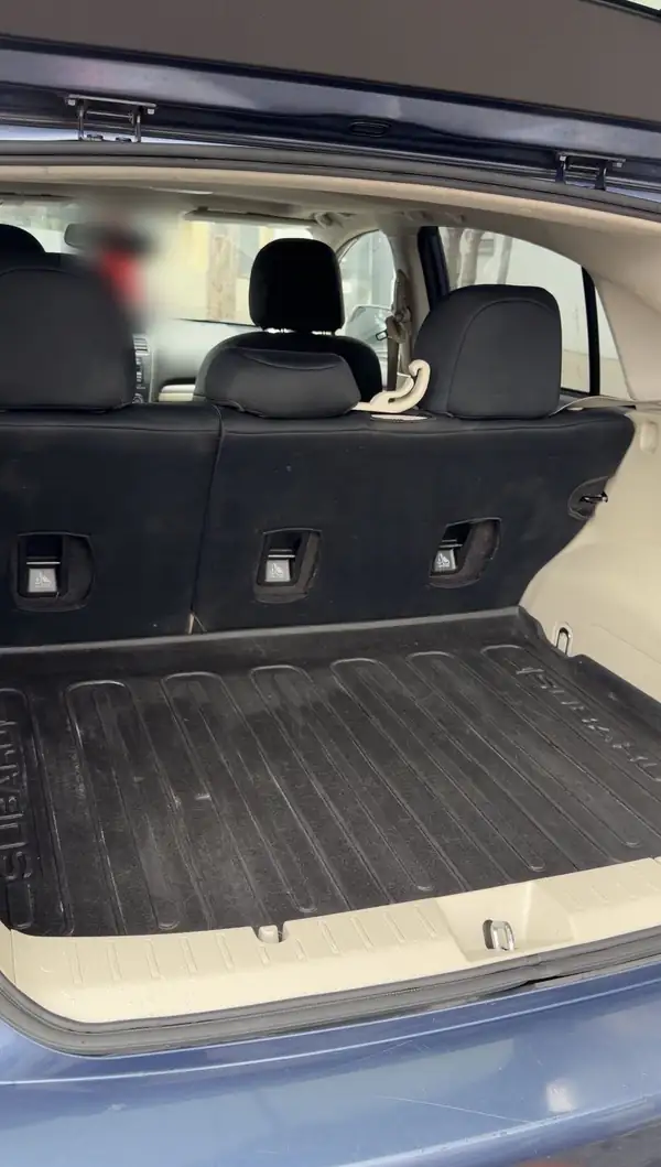 Clean cargo area of a blue Subaru hatchback after detailing, the ribbed Subaru load tray dark and clear of debris.