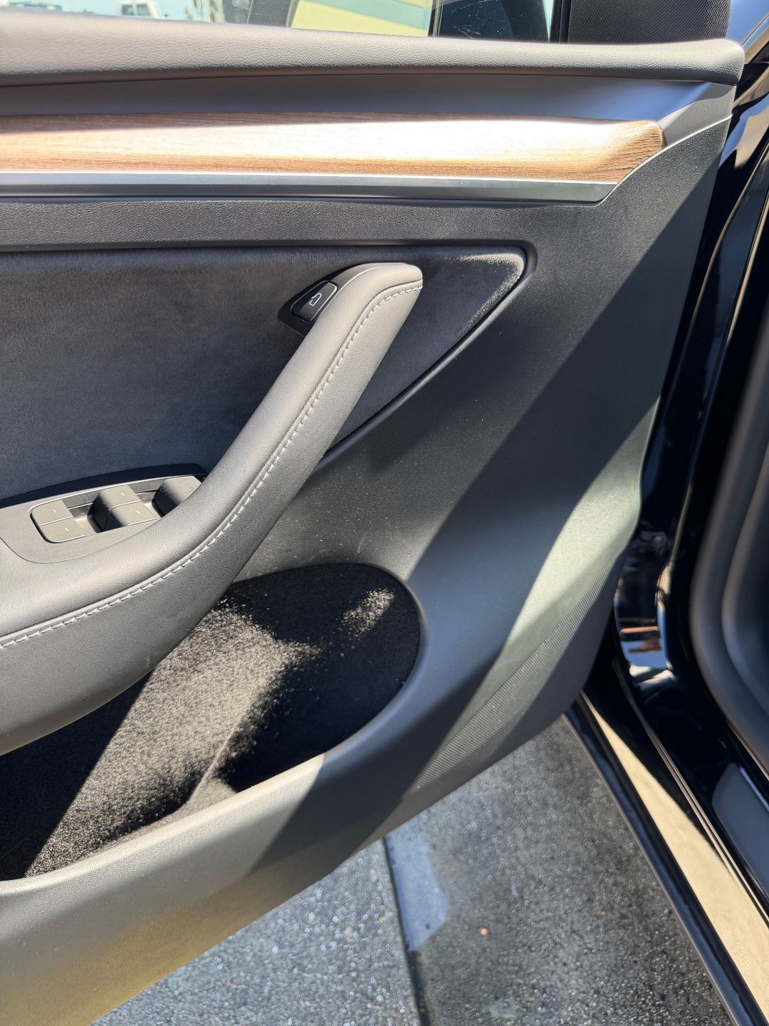Clean front door panel of a black Tesla Model Y after detailing