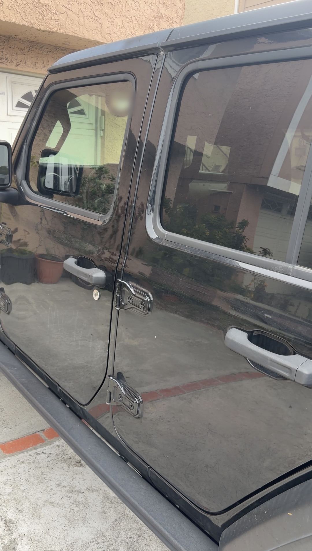 Black Jeep Wrangler side doors parked in a driveway before an exterior detail