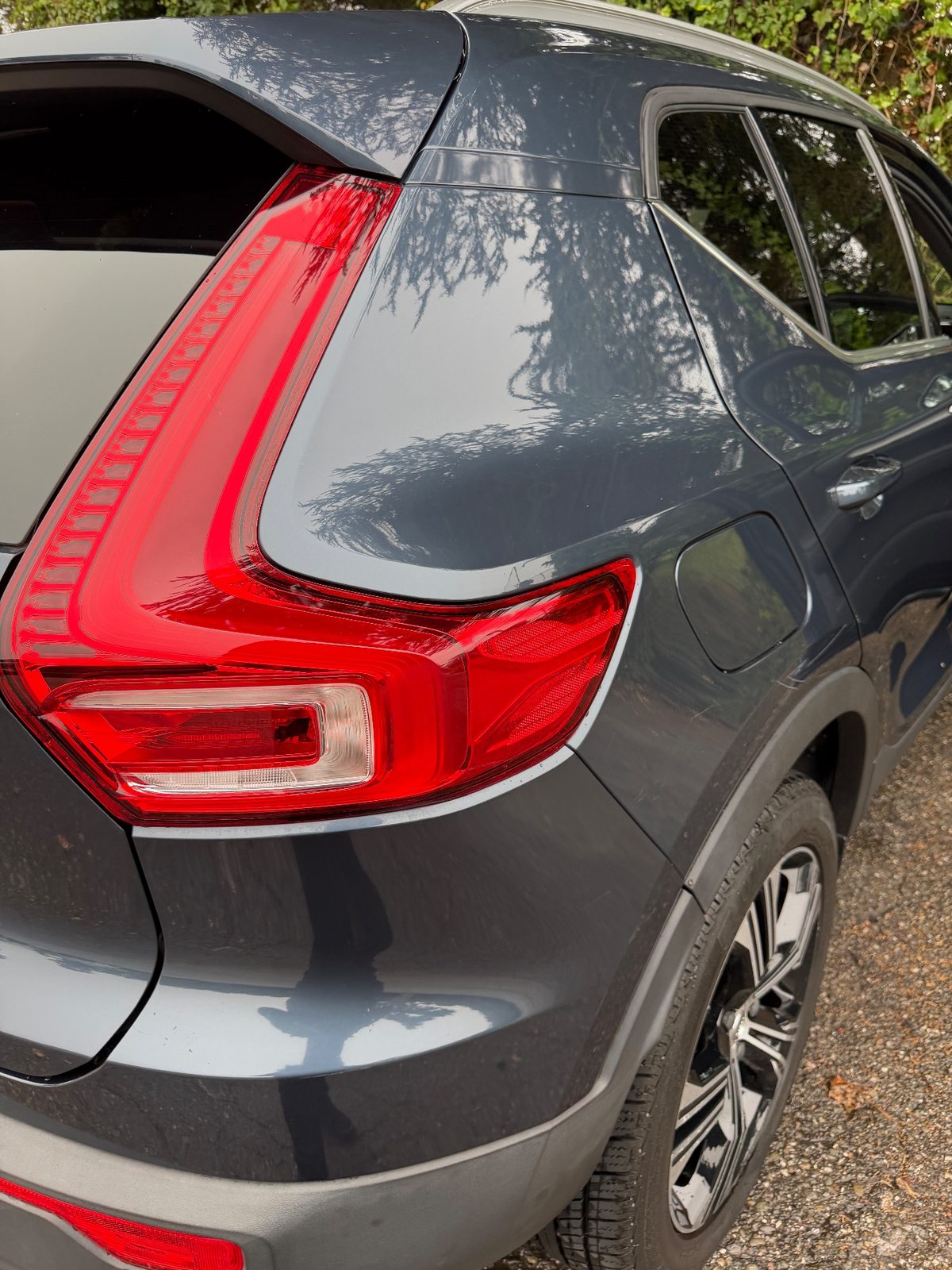 Clean rear right quarter of a Volvo XC40 after washing, with trees reflected in the paint