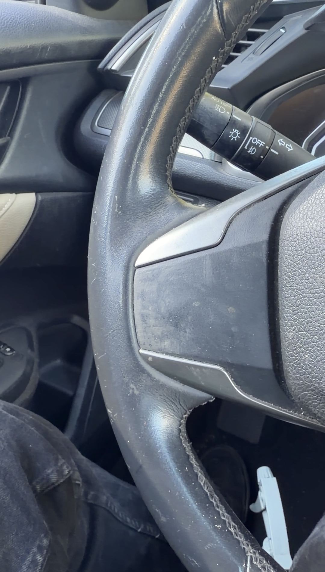 Steering wheel rim and light stalk of a Honda Civic with a dust film before cleaning
