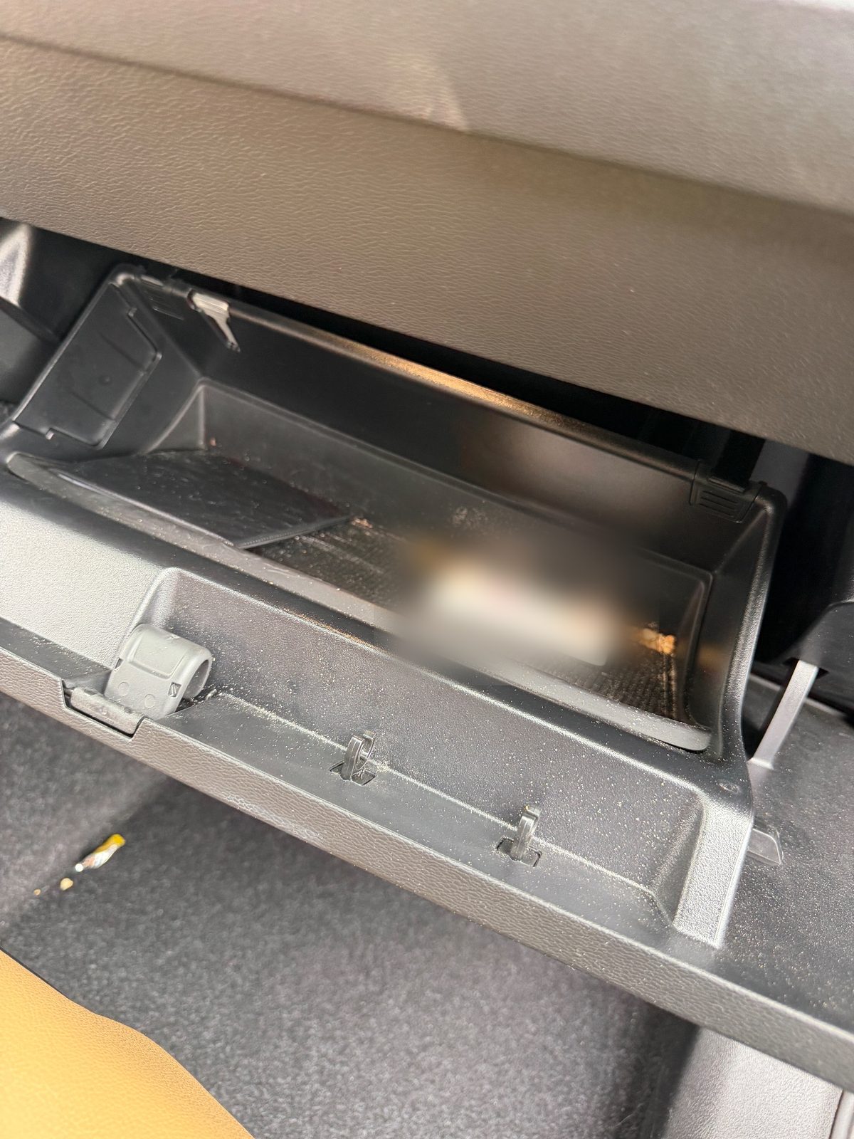 Open glovebox of a Volvo XC40 before detailing, dusty inside