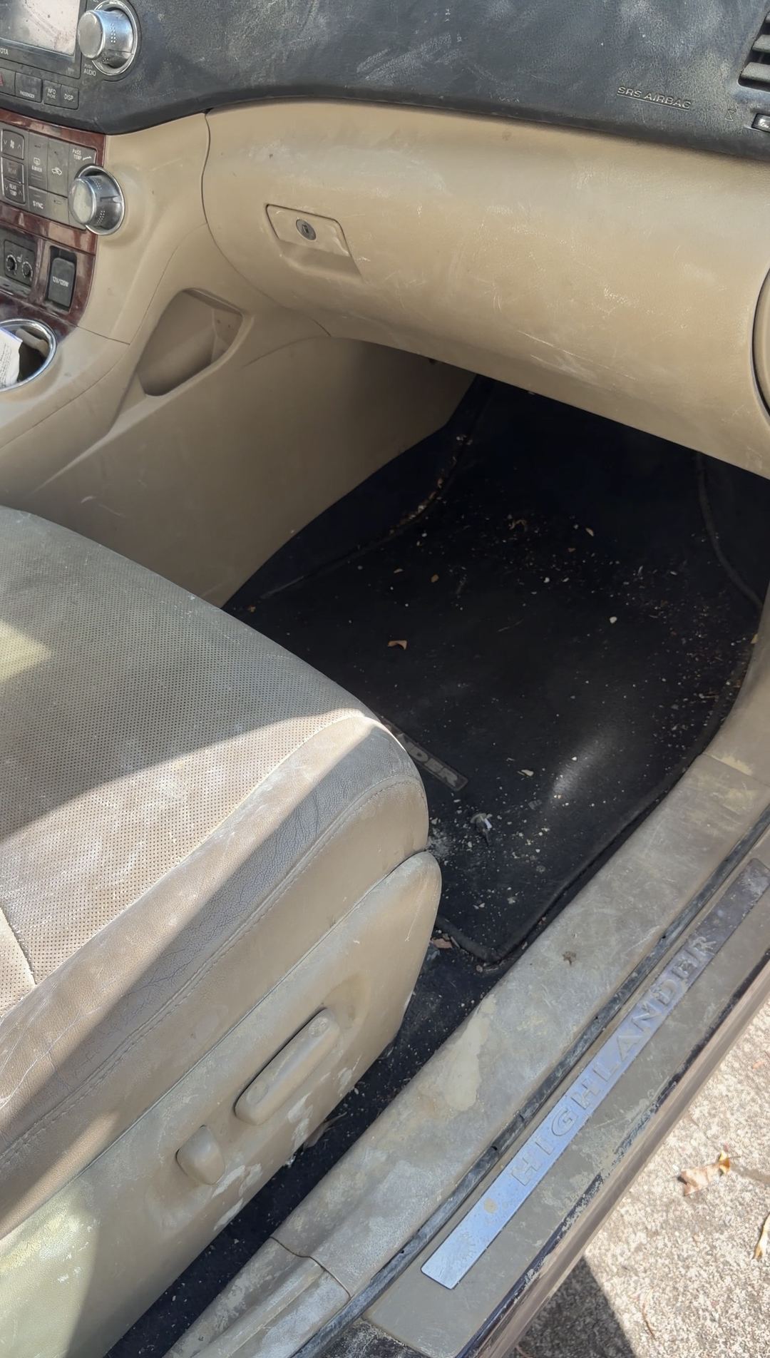 Dusty front passenger footwell and glovebox of a Toyota Highlander before interior cleaning