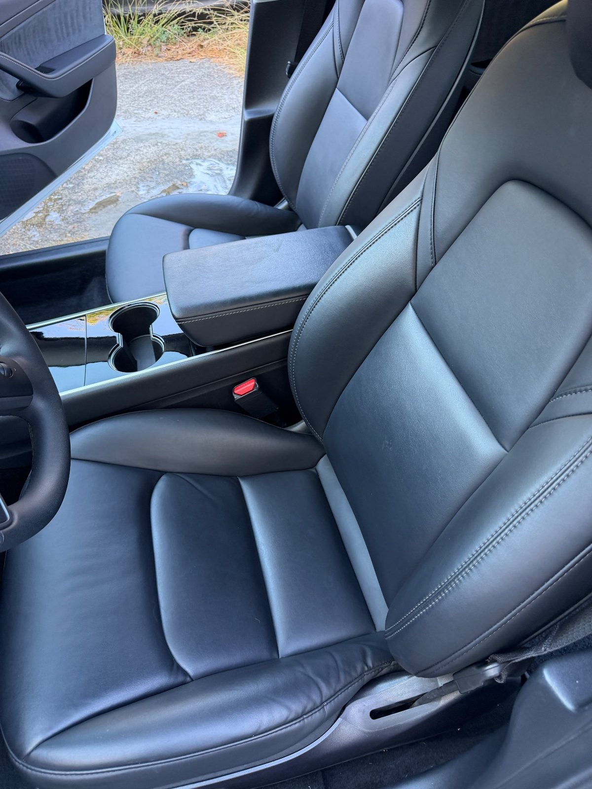 Driver seat of a white Tesla Model 3 after detailing, clean leather and no lint on the belt