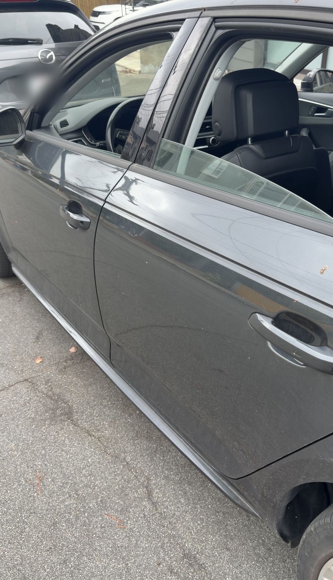 Driver-side doors of a grey Audi A4 with dusty lower panels on a residential street