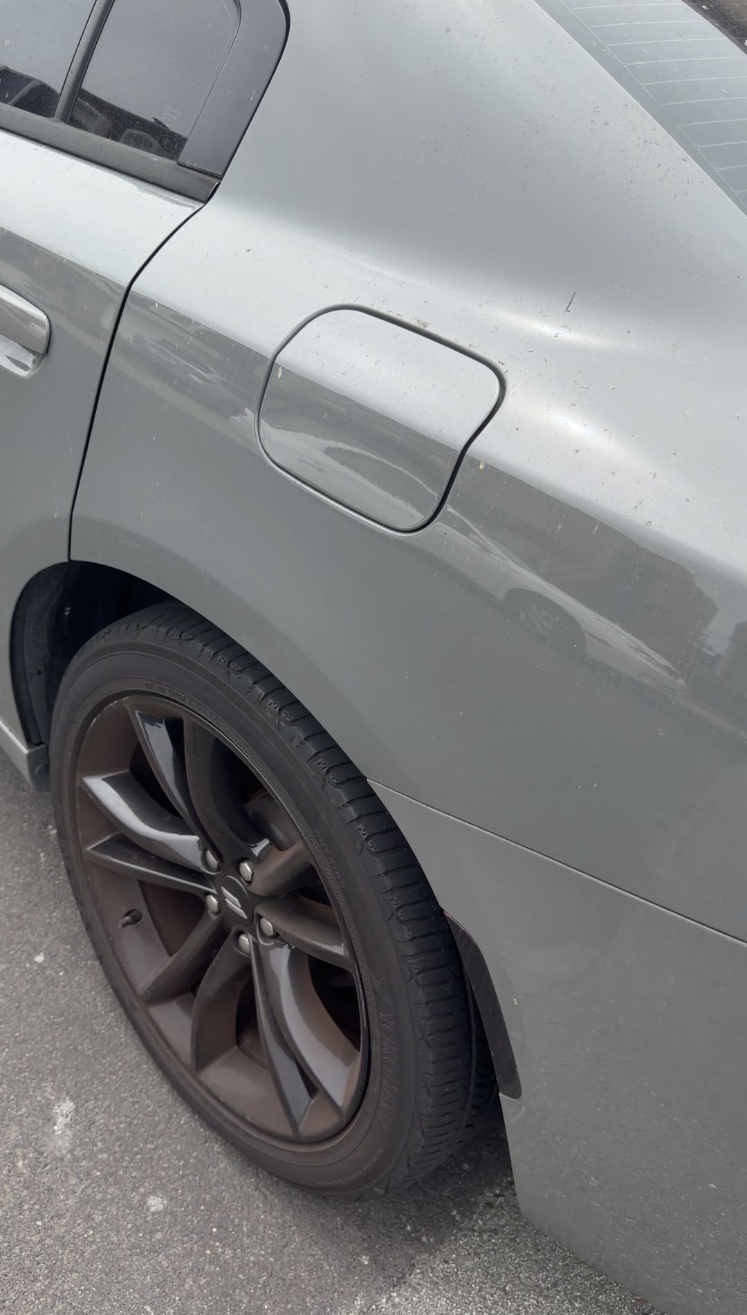 Grey Dodge Charger rear wheel with brown brake dust and a dusty quarter panel before cleaning
