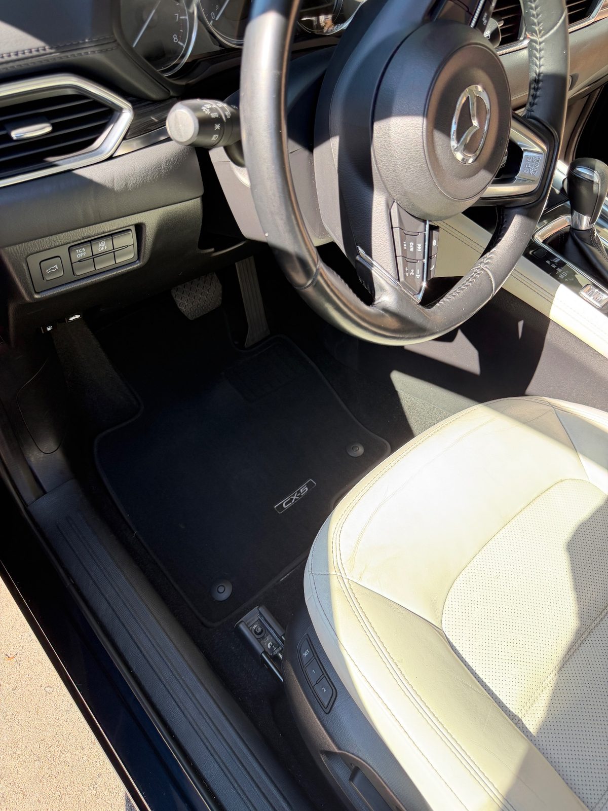 Clean driver footwell of a dark blue Mazda CX-5 after detailing, vacuumed mat with the CX-5 logo
