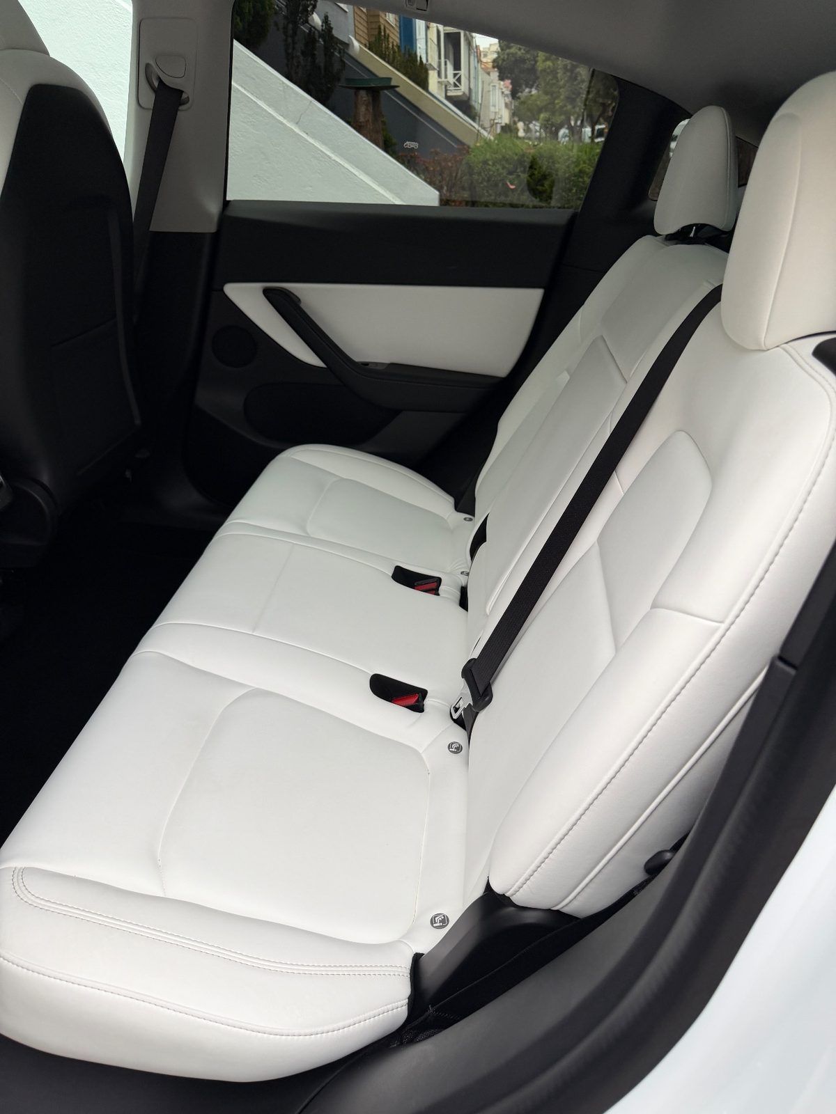 Rear bench of a white Tesla Model Y after detailing, with clean white seats
