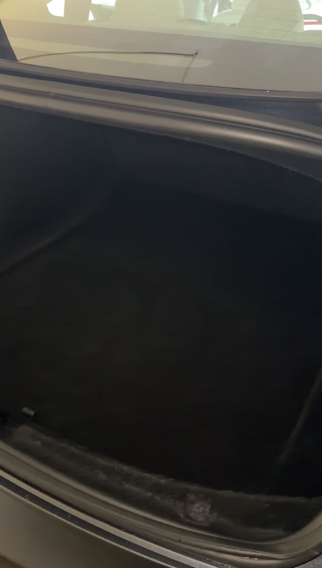 Open boot of a Tesla Model 3 with grit packed into the rubber weatherseal along the sill