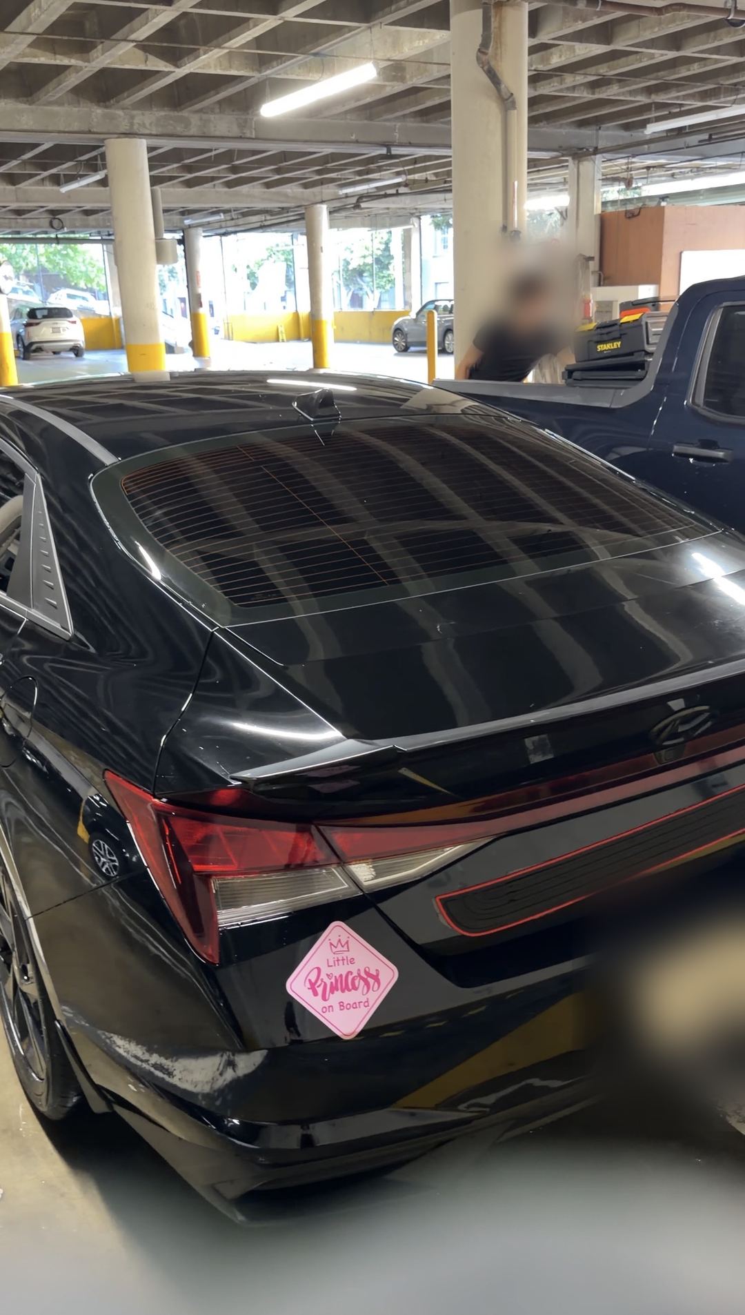 Rear of a washed black Hyundai Elantra with glossy glass and trunk in a parking garage