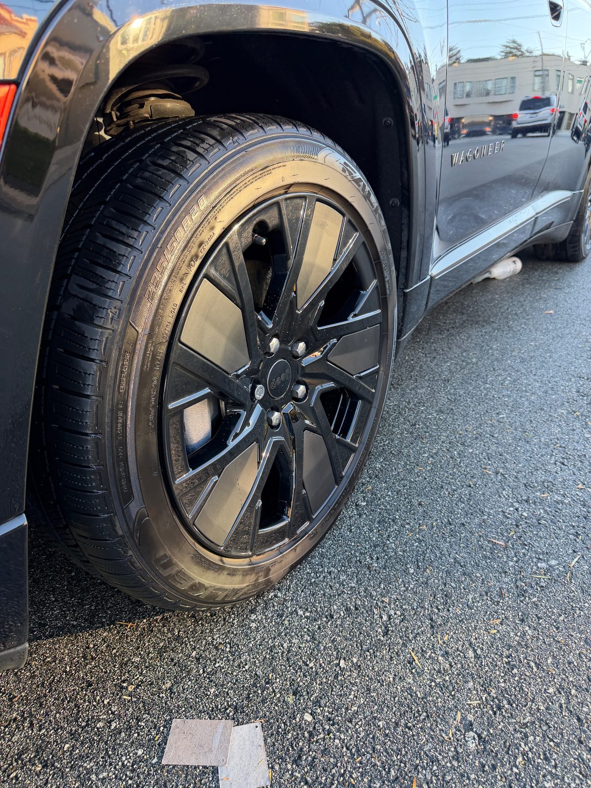 Clean gloss black wheel beside the Wagoneer script on a Jeep Wagoneer S after detailing