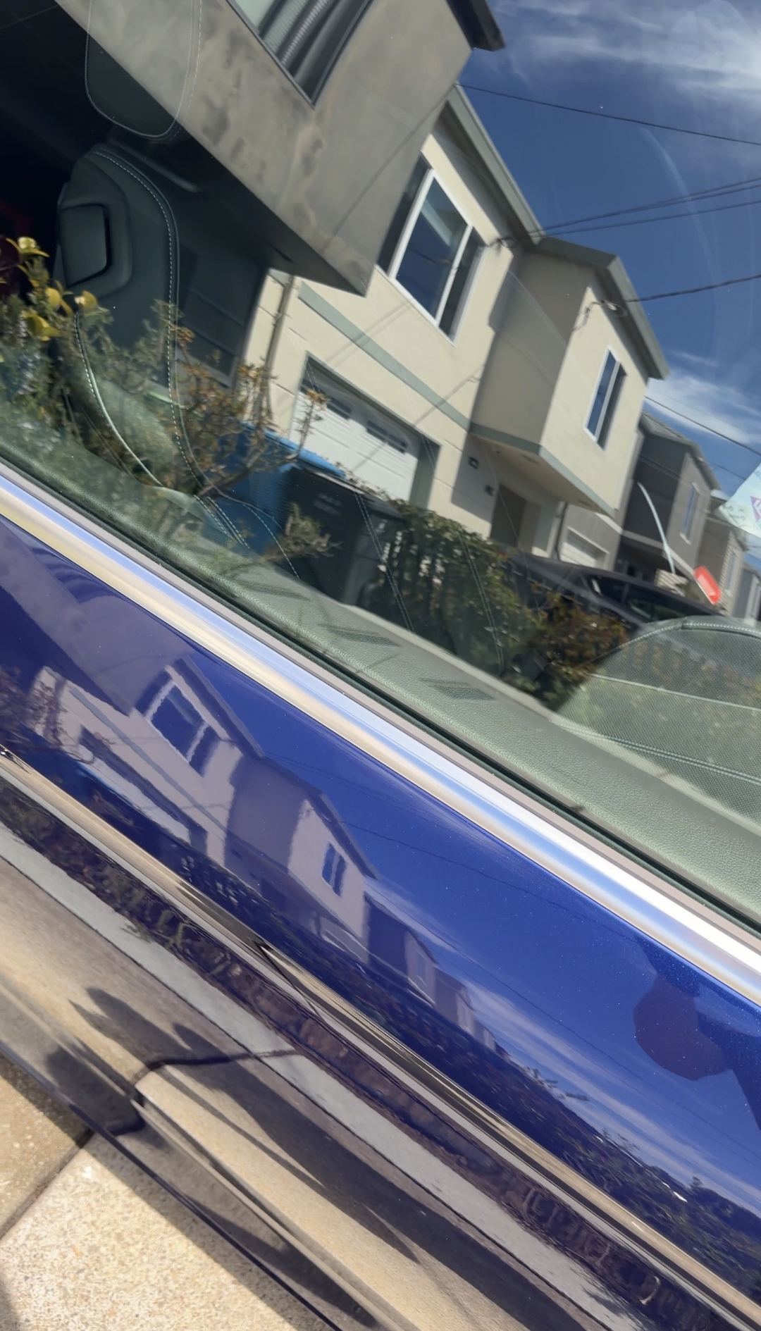 Clean blue door and window trim of an Audi S5 reflecting houses across the street