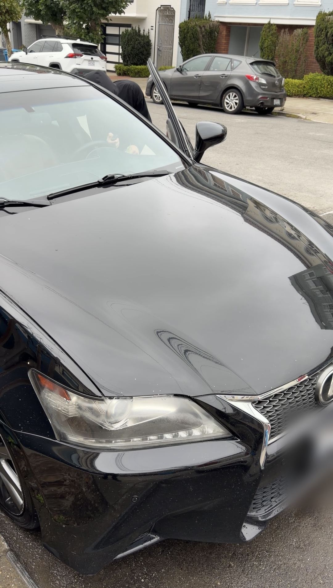 Freshly washed black Lexus GS showing a glossy hood and reflections, parked on a San Francisco street.