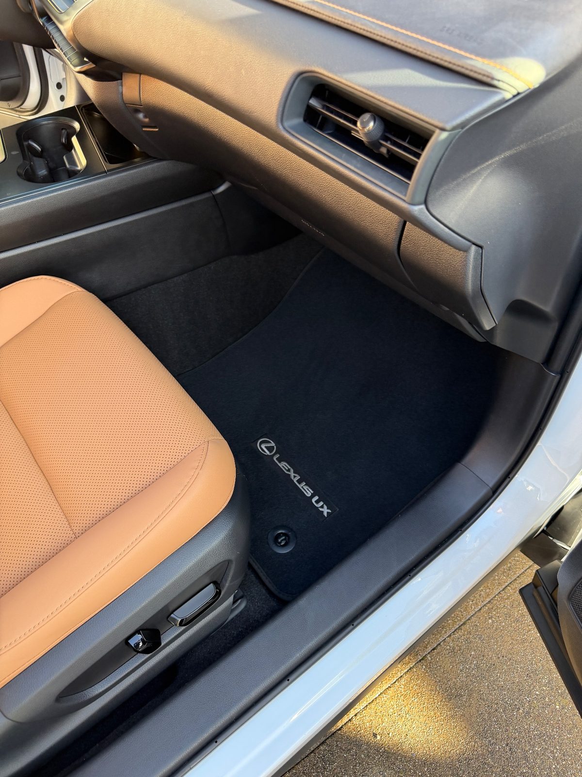 Clean passenger footwell of a white Lexus UX after detailing, mat free of debris