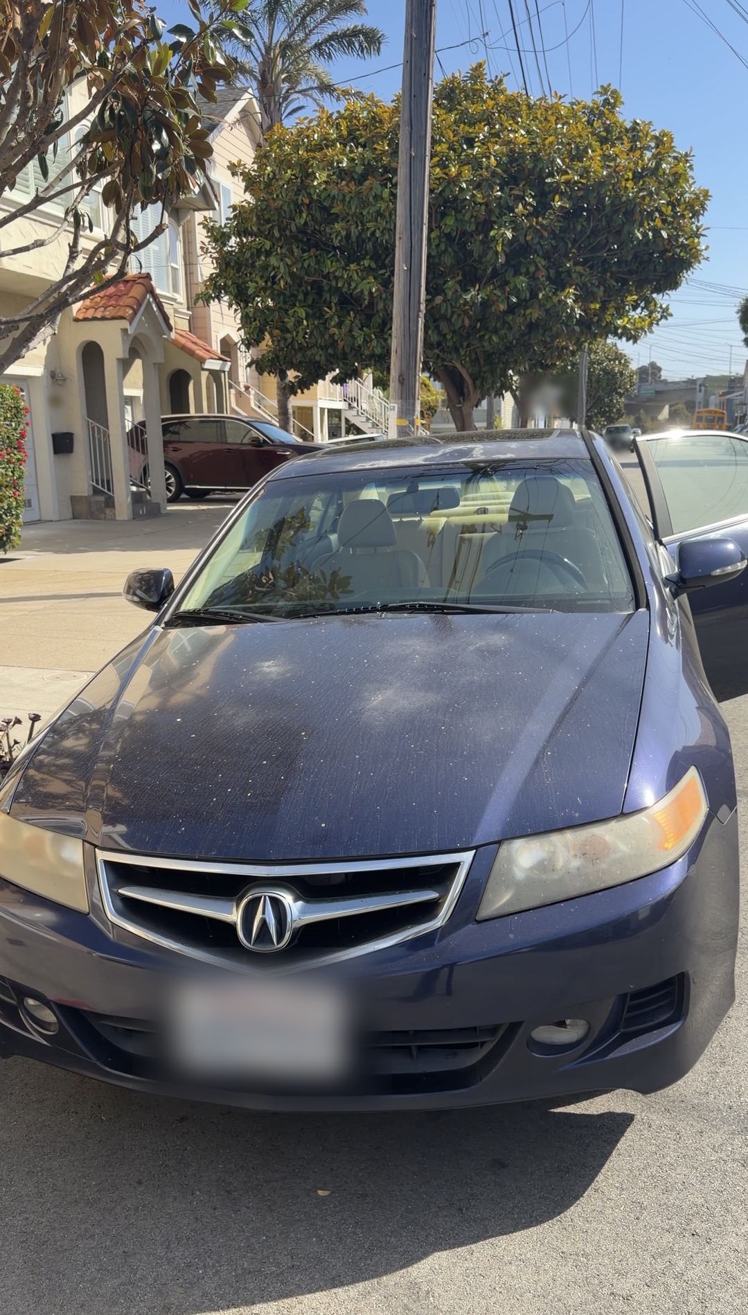 Dark blue Acura TSX parked on a residential San Francisco street, bonnet and roof covered in dust and bird droppings before a mobile detail.