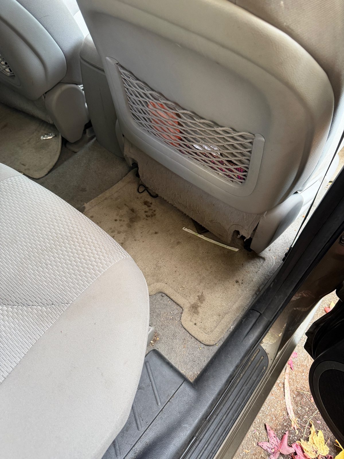 Rear footwell of a 2011 Toyota RAV4 before detailing, stained mat and grit